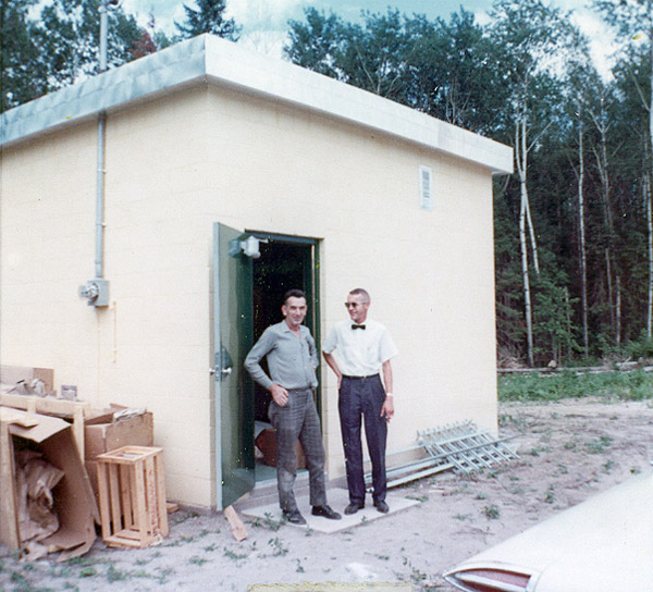 1960 picture of two people outside of a service building with a opened door